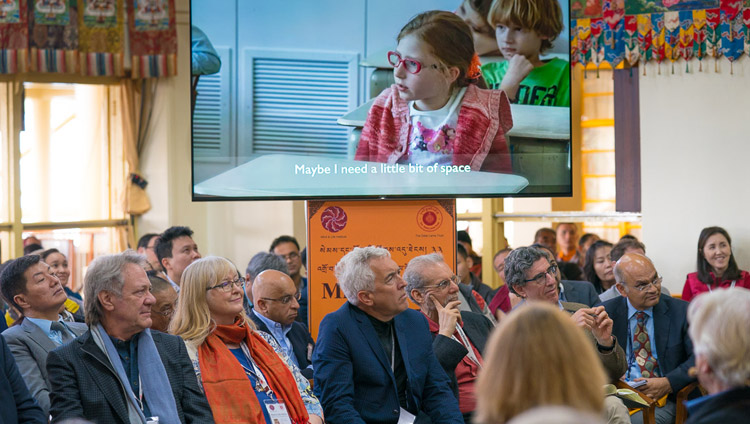 Die Teilnehmenden schauen einen kurzen Filmausschnitt während der Präsentation von Tara Wilkie am zweiten Tag des Mind & Life Dialogs in Dharamsala, HP, Indien am 13. März 2018. Foto: Tenzin Choejor