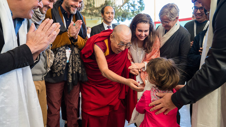 Seine Heiligkeit der Dalai Lama grüsst ein kleines Mädchen bei der Ankunft im Tsuglagkhang zu Beginn des Mind & Life Dialogs in Dharamsala, HP, Indien am 16. März 2018. Foto: Tenzin Choejor