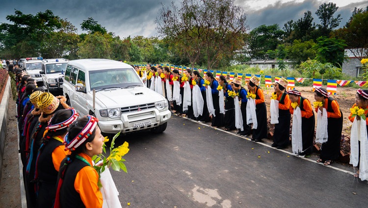 Studierende in traditionellen Kleidern säumen die Strasse um Seine Heiligkeit den Dalai Lama am Dalai Lama Institute of Higher Education zu begrüssen - in Sheshagrihalli, Karnataka, Indien am 13. August 2018. Foto: Tenzin Choejor