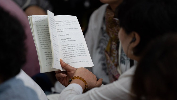 Jemand im Publikum verfolgt den Text der Unterweisungen von Seiner Heiligkeit dem Dalai Lama im tibetischen Haupttempel in Dharamsala, HP, Indien am 5. September 2018. Foto: Tenzin Choejor